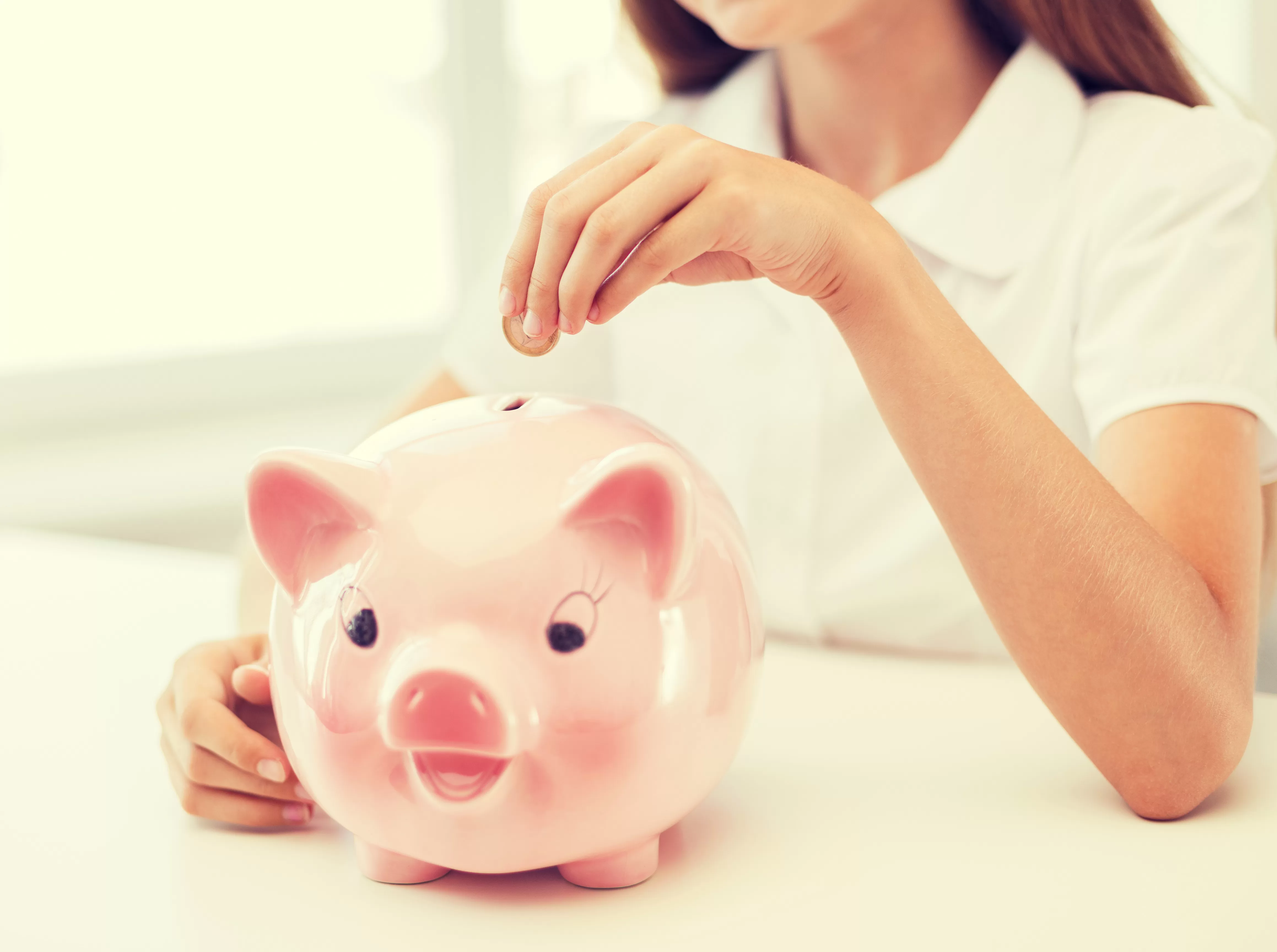 Smiling child putting coin in piggy bank